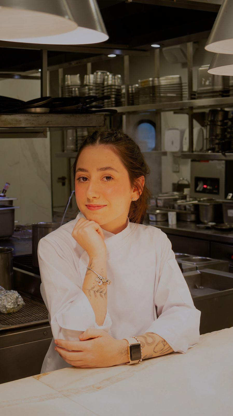 Julia Di Loreto apoiada na bancada da cozinha.